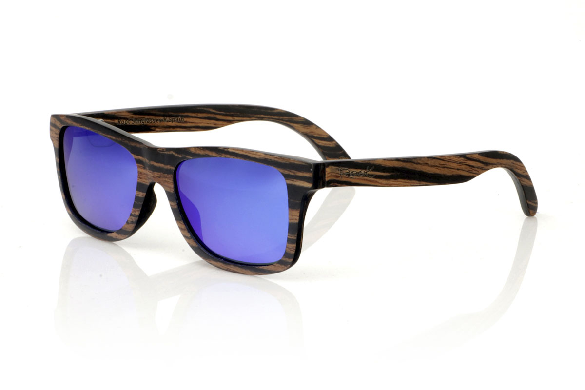 Wood eyewear of Ebony modelo PARIS. PARIS wooden sunglasses feature a classic silhouette with a more square touch and a medium size, ideal for those looking for a timeless style with a perfect fit. This model is entirely made of African ebony wood, with an impressive grain in black and brown tones, which provides an air of sophistication. With measurements of 148x45 and a caliber of 54, the PARIS are perfect for those who value durability and design in their accessories. This pair is not only a complement to your outfit, but a statement of style and appreciation for natural details and quality craftsmanship. | Root Sunglasses® 